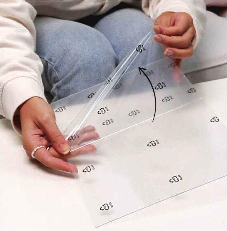 Schutzfolie wird von klarer Acrylglasscheibe eines Vario Bilderrahmens entfernt